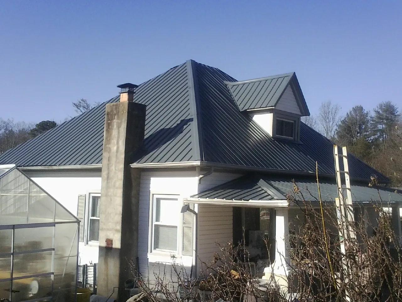 Dark blue standing seam metal roof on a white farmhouse with dormer — Slate & Tile Roof Repair by Roofing Brothers in Churubusco
