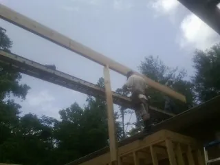 Carpenter setting a ridge beam over a new addition frame — Ice Dam Removal by Roofing Brothers in Churubusco