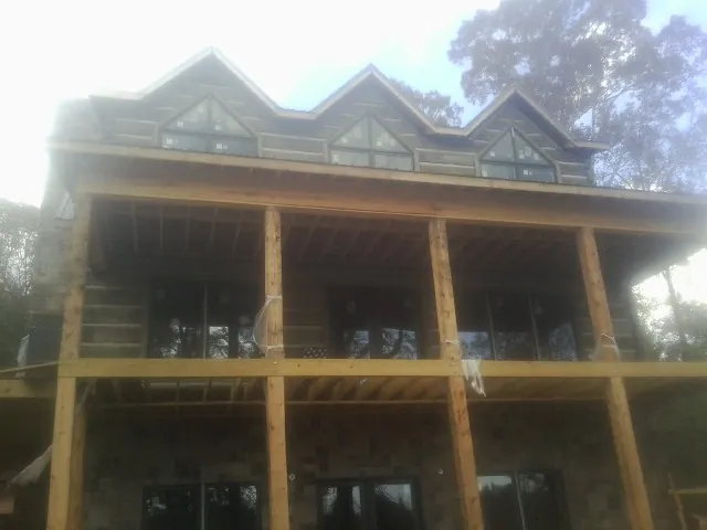 Dormers and porch framing on a large log home under construction — Roof Coating work by our crew in Churubusco