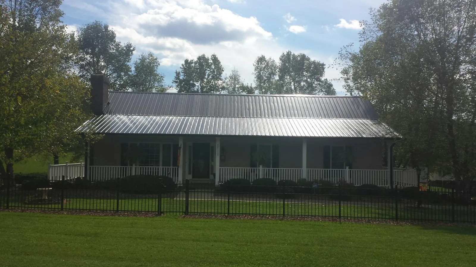 Gray metal roof on a brick ranch with a full width front porch — Gutter Guard Installation work by our crew in Churubusco