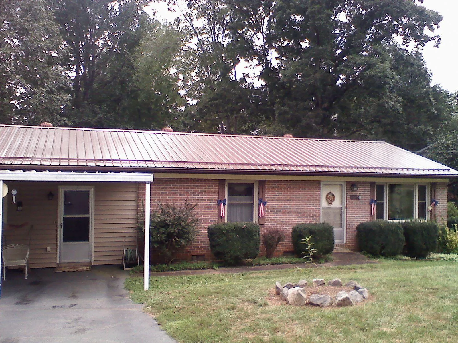 Bronze metal roof and carport on a brick ranch home — Roof Repair work by our crew in Churubusco