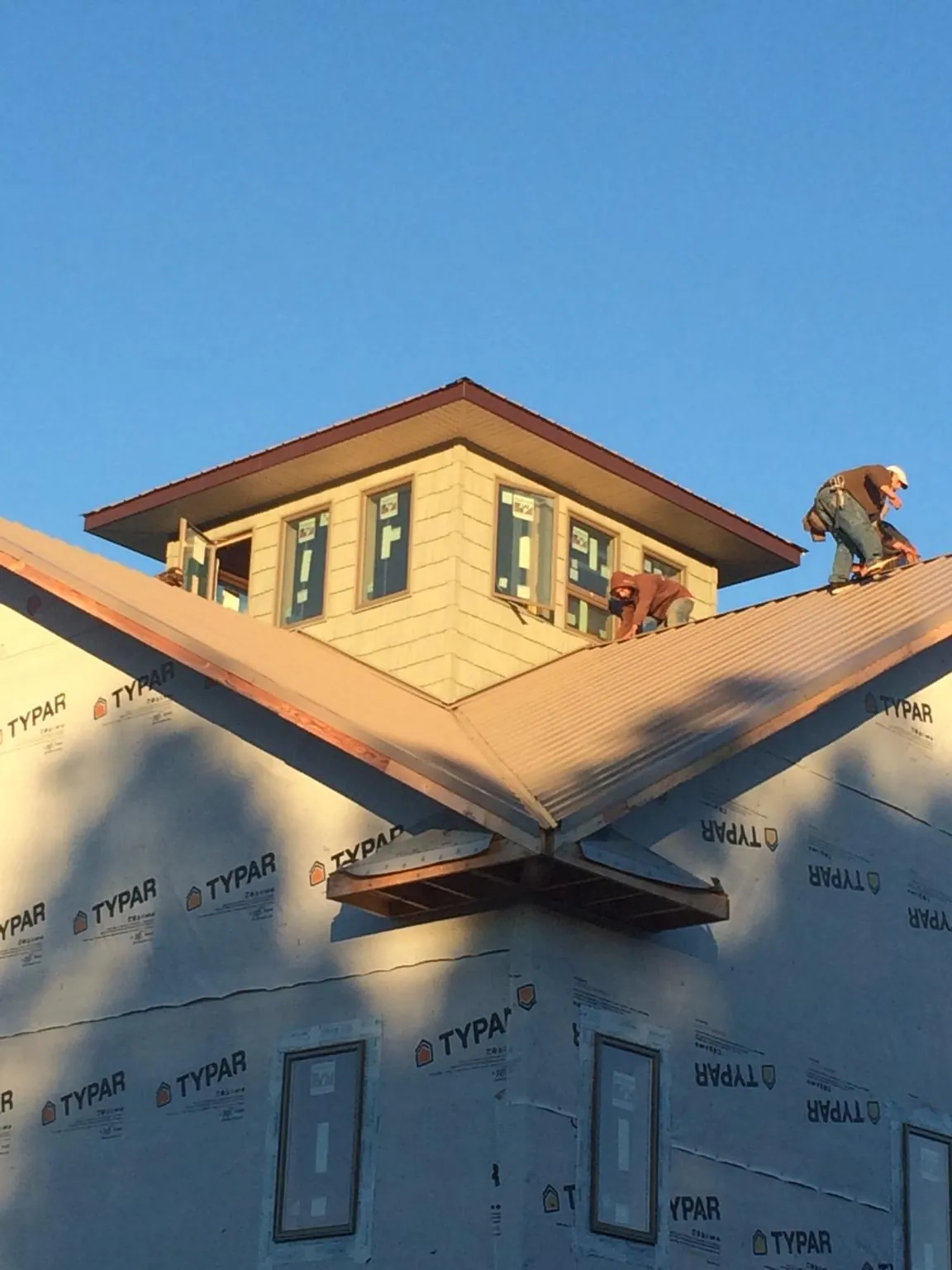 Roofers working around a rooftop cupola on a new metal roof at sunset — Roof Waterproofing in Churubusco by Roofing Brothers